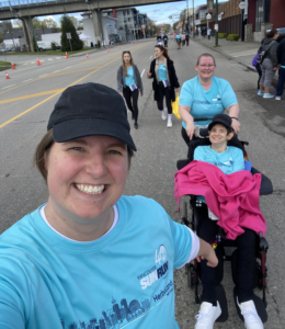 two women assist a third woman using a wheelchair in a fun run